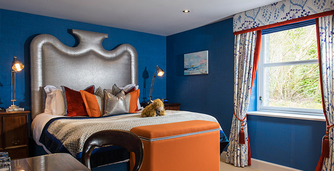 Luxuriously decorated hotel room with a bold blue and orange color scheme at The Torridon Hotel, featuring elegant bedding.