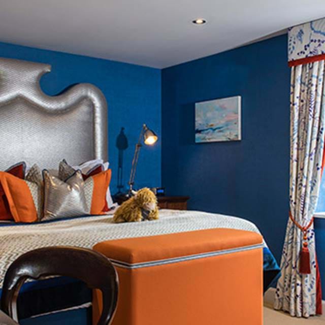 Luxuriously decorated hotel room with a bold blue and orange color scheme at The Torridon Hotel, featuring elegant bedding.